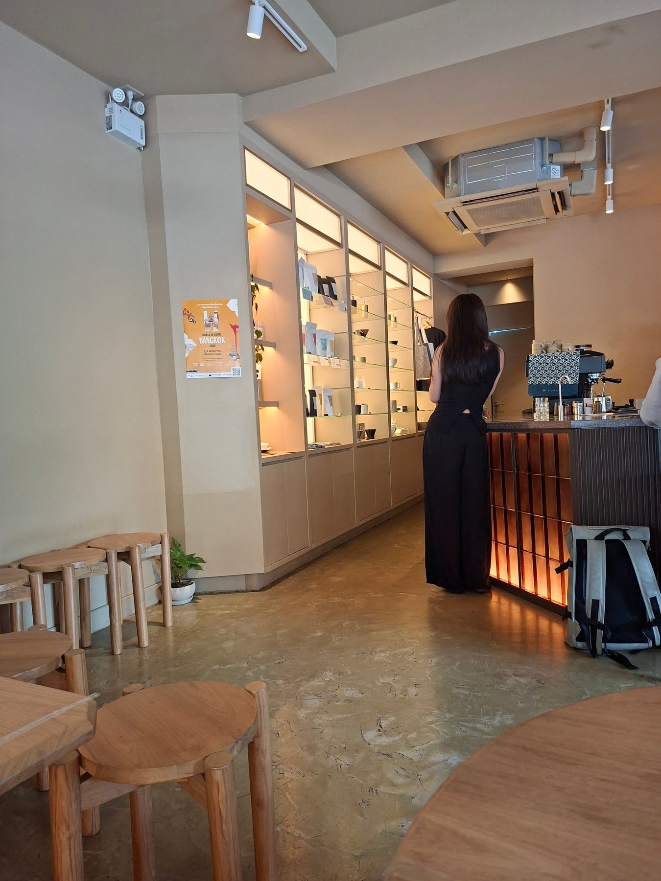 The minimalist Kurasu Bangkok café interior with pale wood seats and a softly lit coffee counter