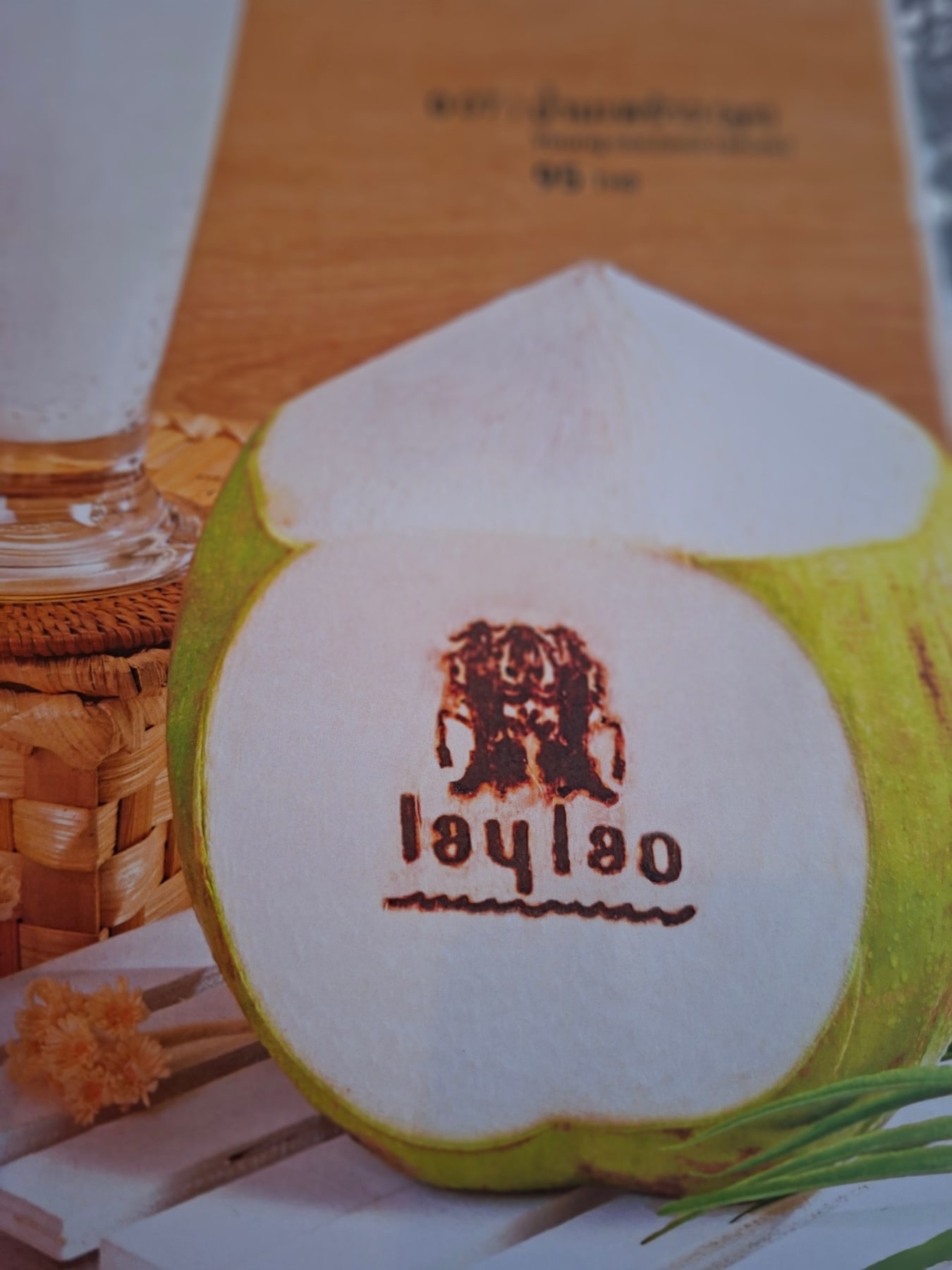 Fresh coconut stamped with the Lay Lao logo beside a drink on the restaurant table