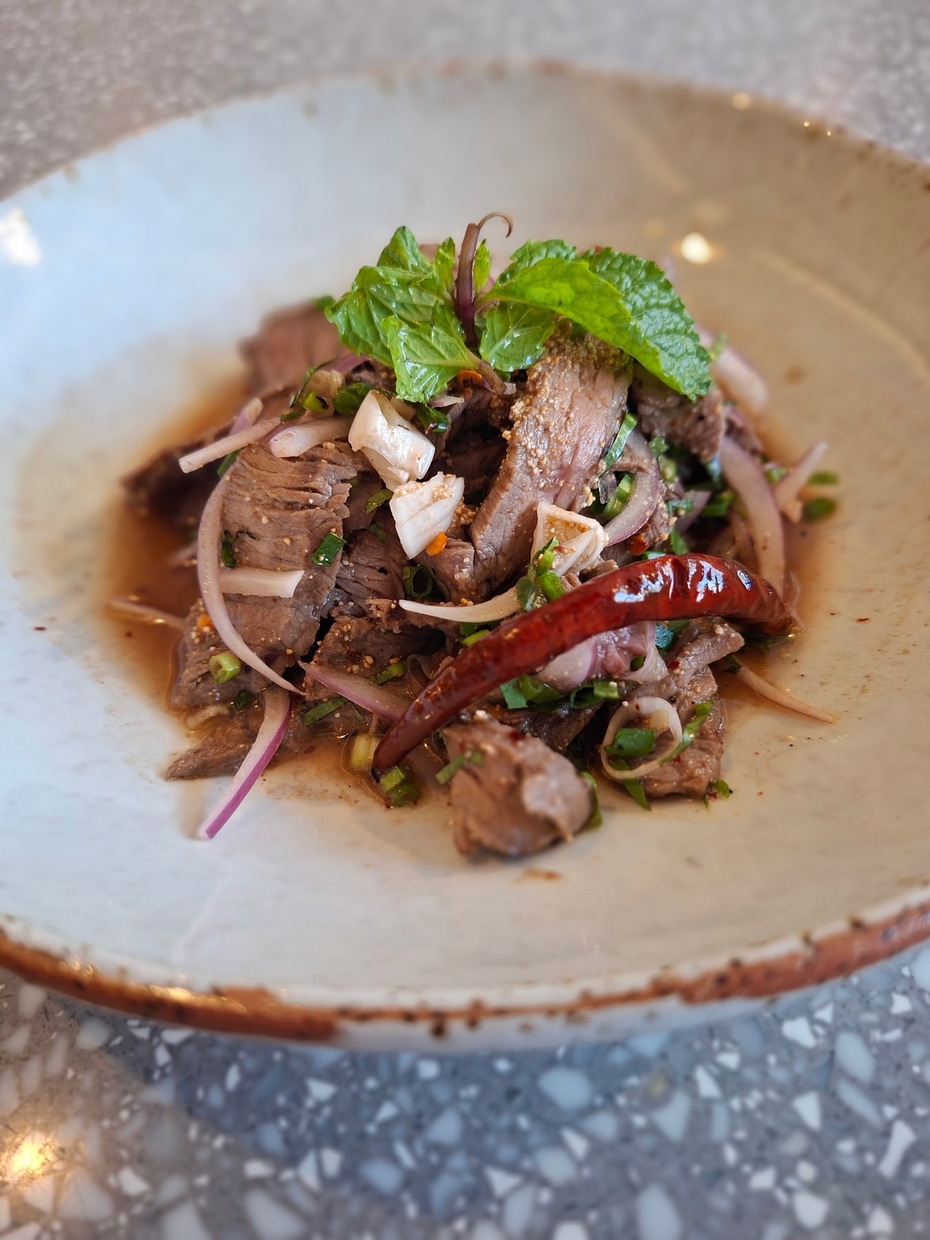 Sliced grilled Thai-French beef salad with herbs and dried chilli